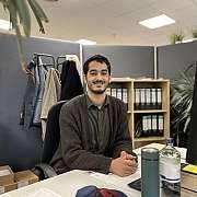 junger Mann sitzt am Schreibtisch und lächelt