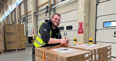 fröhlicher Mann an Pallettenwagen